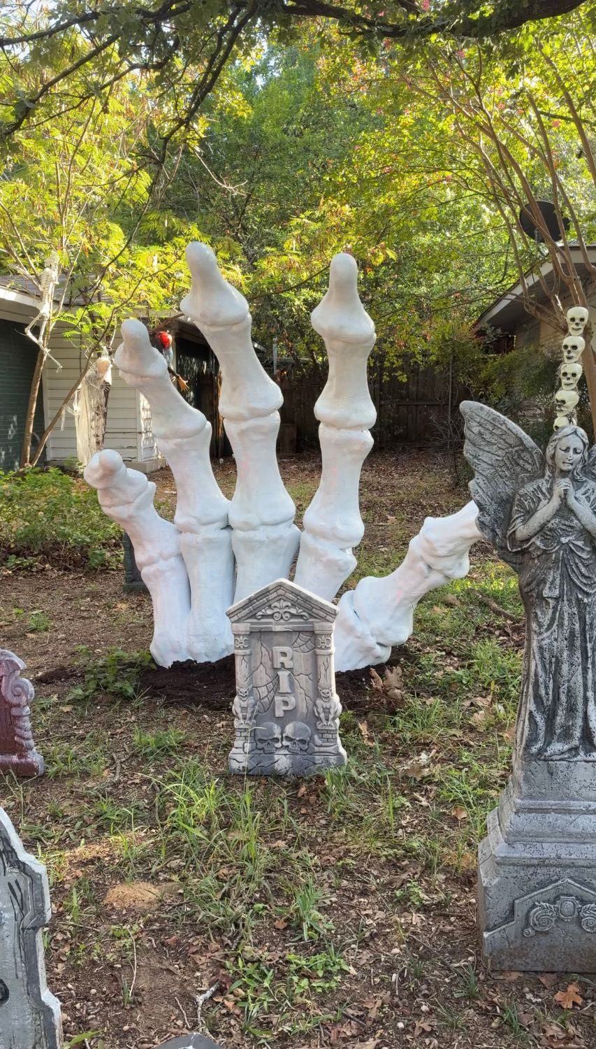 A 6 ft 3D printed skeleton hand standing in a yard